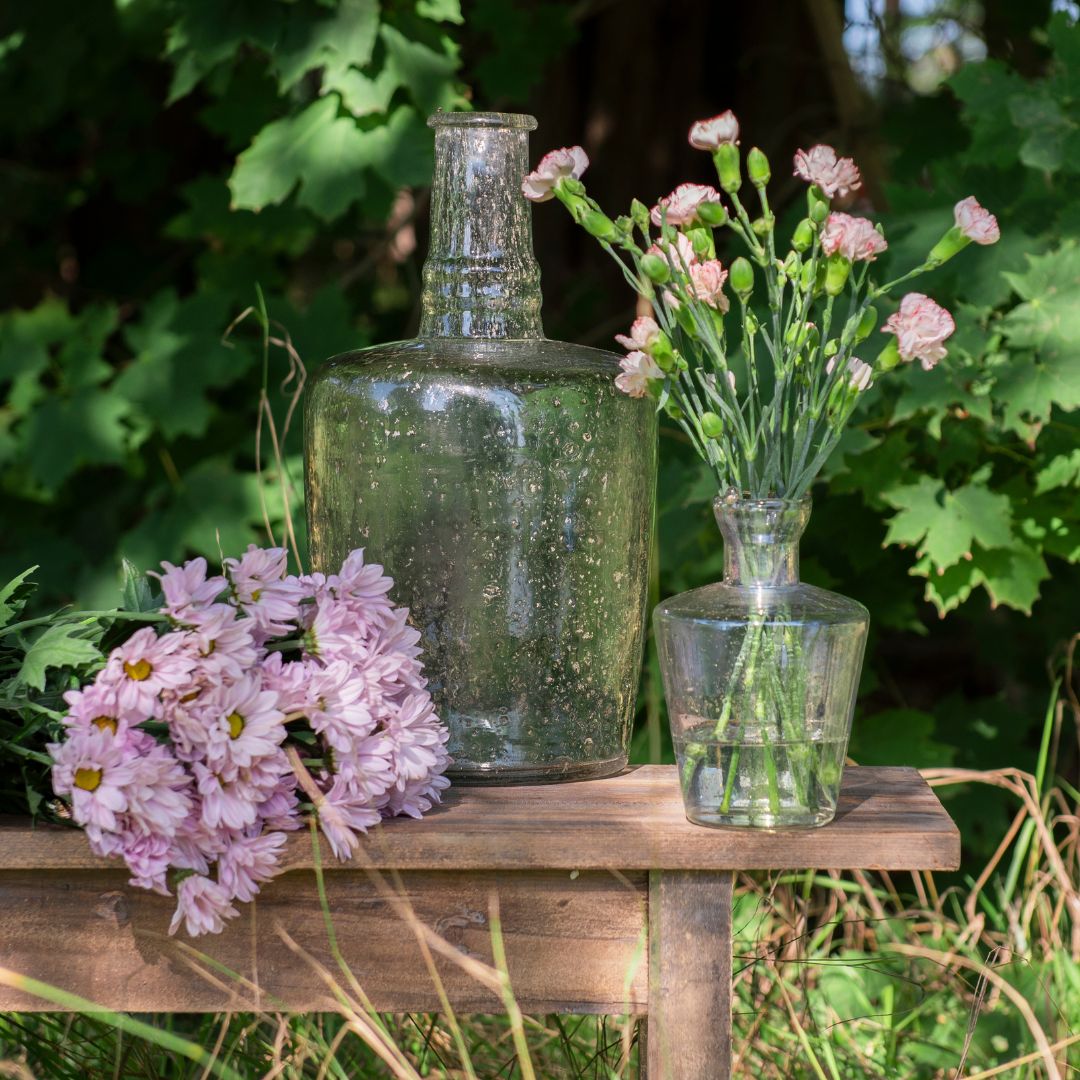 Glazen vaas en glazen fles met roze bloemen