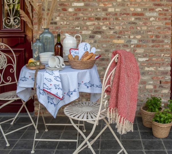 A bistro set adorned with a fish-themed tablecloth. The table is set.