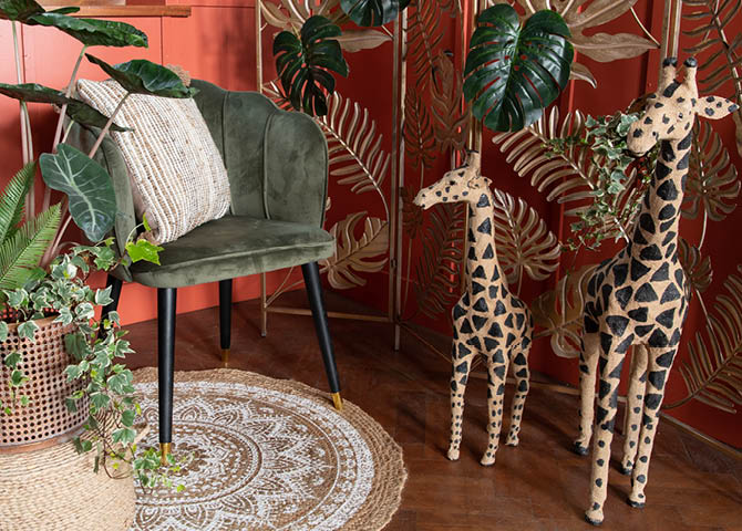 Een tapijt, een stoel met een kussen, planten en beelden van giraffen.