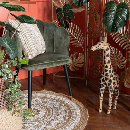 Een tapijt, een stoel met een kussen, planten en een beeld van een giraffe.