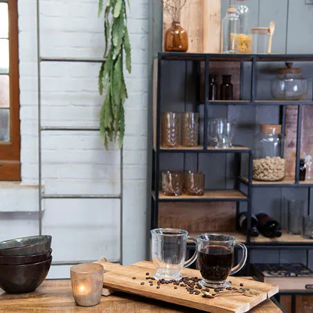 Un placard avec des bocaux en verre, des tasses à thé, des bols, une planche à pain, un porte-serviettes et une bougie dans un style industriel.